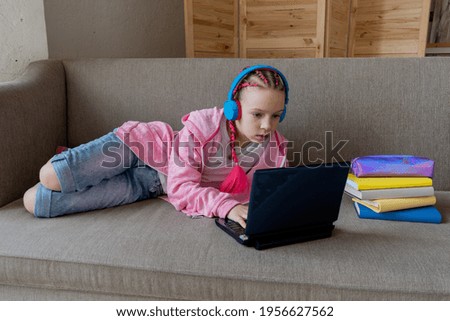 Girl work on laptop while lying the sofa in room at home. Concept education is process teaching at school. Teenager studying the computer. Copy space