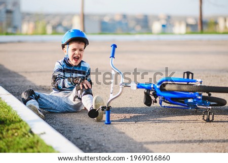 A small child fell from a bicycle crying and screaming in pain.