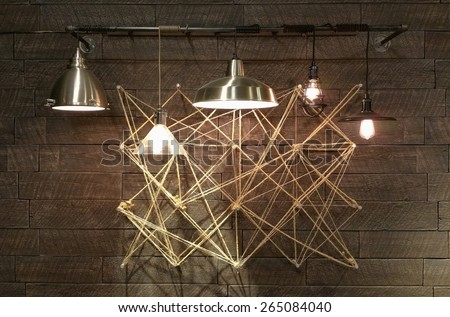 Modern light fixtures hanging in front of complex geometrical design. Abstract Interior design modern and minimal. Light bulbs displaying brightly.