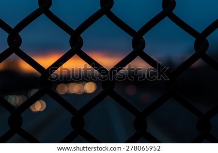 Chain link fence on an evening sunset with depth of field, out of focus sunset. Sunset with amazing sunset background. Industrial sunset.