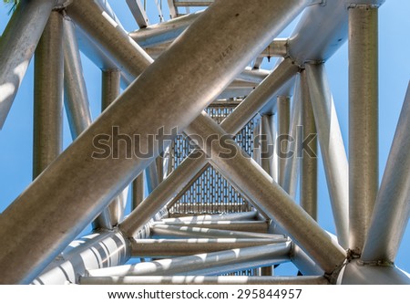 Complex ladder. Urban geometry, Street photography, Complex design. Modern art. Abstract art design.Steel beams. Industrial art. Industrial design. Blue sky background. Industrial geometry. Steel art,
