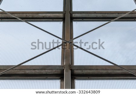 Steel industrial window frame with steel cable support. Industrial window sill with screen and blue sky background. Urban geometrical design. Geometrical pattern interior architecture. Minimal design.
