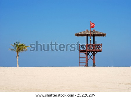 Red flag on the beach. A lifeguards hut ant palm tree.