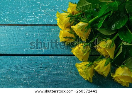 Yellow roses on a blue wooden background. Empty space for text