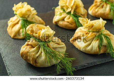 Pancakes with salmon, cream cheese and herbs. Bags tied with dill on a slate board. Selective focus