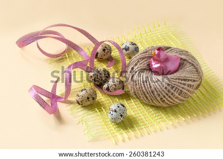 Easter composition: decorative hen nest, eggs and ribbon on a green straw and yellow background