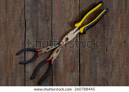 Pliers with rubber handles, decorated with yellow and red accents on a wooden surface