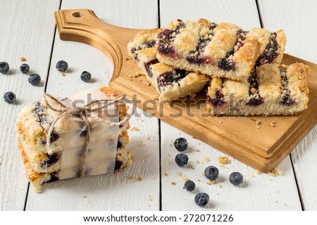 Sliced cake with blueberry jam on a cutting board, packed tile cake, berries on a white background