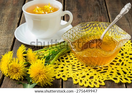 Flower tea in a white cup, jam of dandelions and flowers dandelions on a yellow  knitted napkin. Selective focus