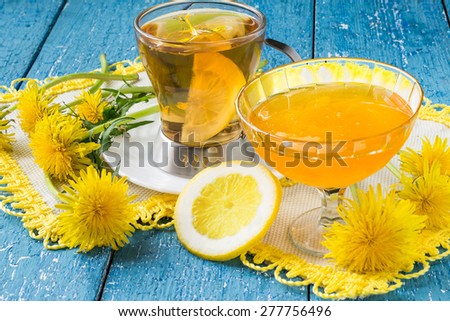 Flower tea with lemon, flowers and jam of dandelions on a blue wooden background