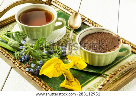 Vintage tray with Breakfast: delicious fresh cupcake in a cup of tea, a bouquet of flowers to set the mood. Selective focus