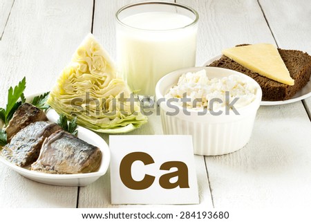 Foods rich in calcium (sardines in oil, cabbage, milk, cottage cheese, brown bread, cheese) on white wooden table