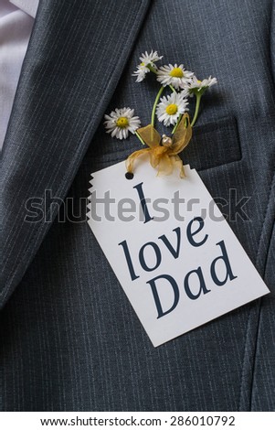 Men\'s jacket with the inscription on the card: I love dad and chamomile in a jacket pocket