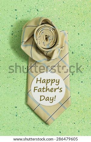 Composition for Father\'s day - tie and sticker with the words: Happy Father\'s Day on a green colored background