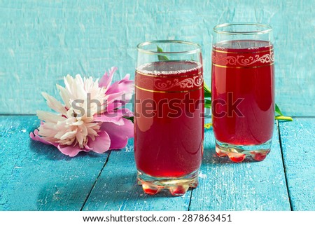Fresh summer cooling drink with cranberry juice and peony on a blue wooden background