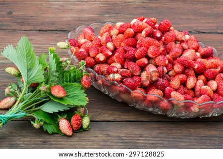 Lots of fresh ripe wild strawberry in the oval dish, a bouquet of strawberries on a wooden table. Selective focus