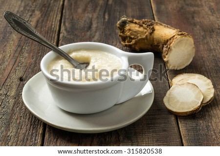 Pungent spices prepared of horseradish for the meat in a gravy boat on a wooden table. Selective focus