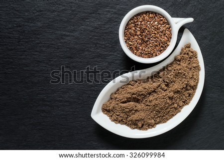 Source of vitamins groups B, fiber, Omega 3, potassium, magnesium and antioxidants - flax seeds and flour on the surface of the slate with copy space