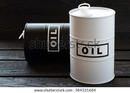White and black barrels with oil on a wooden background. Selective focus