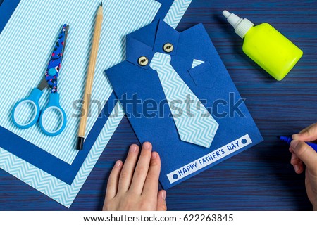 Making greeting card for Father\'s Day. Children\'s art project. DIY concept. Step-by-step photo instruction. Step 10. Child makes the inscription: Happy Father\'s Day