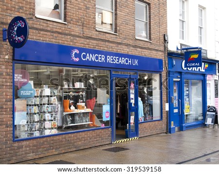 Andover, High Street, Hampshire, England - September 21, 2015: Cancer Research UK retail store, the worlds largest independent cancer research charity, late rain soaked afternoon