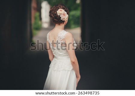 Bride with beautiful hairdo standing back a lace wedding dress