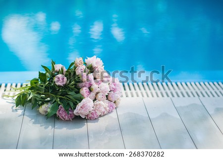Pink and white bouquet of peonies on the background of blue water