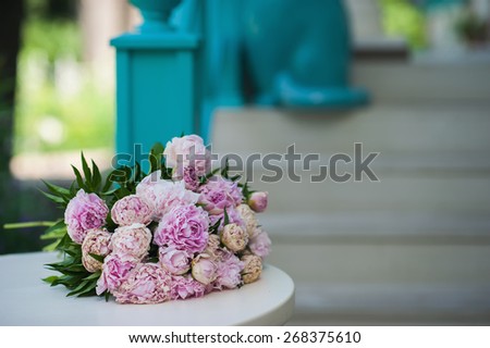 Pink and white bouquet of peonies lies on a white table