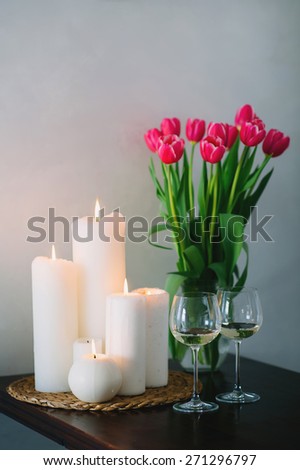 Table with a beautiful bouquet of pink tulips with candles and two glasses of wine, lifestyle, romance