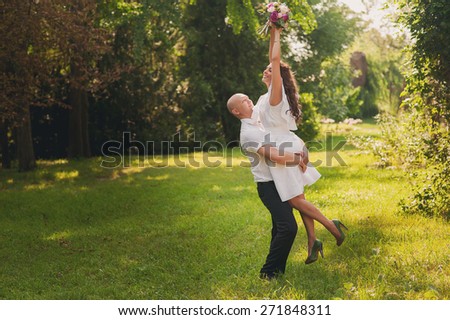 A man holding a happy girl in her arms, she was with a wedding bouquet in hand, they are happy and laughing, lifestyle-concept