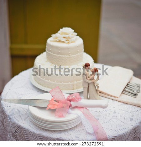 A beautiful wedding cake with a knife and decorating wedding statuette