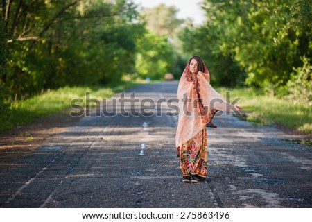 Beautiful young girl in an Indian dress walking along the road in the summer