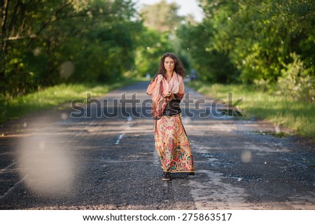 Beautiful young girl in an Indian dress walking along the road in the summer