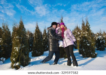Young beautiful family in bright clothes choosing a Christmas tree, snow, lifestyle, winter holidays