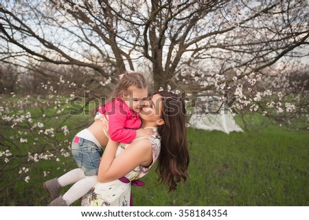 Mom plays with her daughter in the lush spring garden, smiling, family, love
