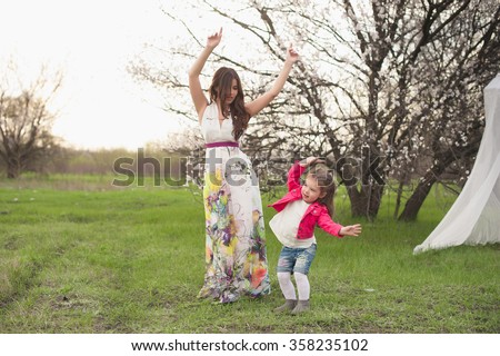 Mom and daughter dancing in nature together, the family, motherhood, entertainment, recreation, game