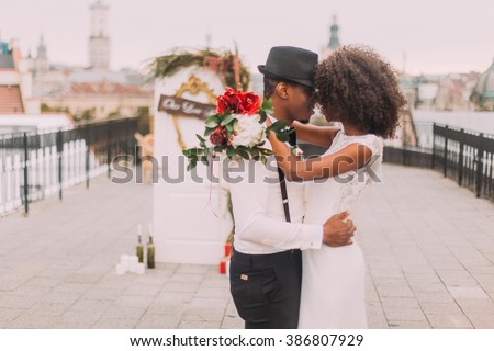 Happy black wedding couple softly hugging on the rooftop during the wedding ceremony