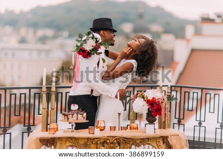 Stylish african wedding couple having fun on the balcony with luxury golden table in oriental style on foreground