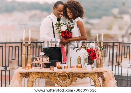 Charming black wedding couple holding handes on the terrace