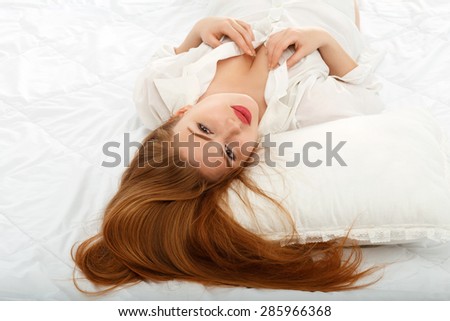 Portrait of a beautiful sexy girl lying on the back in bed in a man\'s shirt