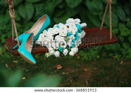 Attributes runaway bride. Wedding bouquet of white roses and blue ribbons and blue patent leather high-heeled shoes