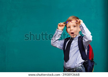 little Boy in eyeglasses with big backpack. School, kid, rucksack. Cheerful smiling little boy opens his mouth in surprise. Looking at camera. School concept. Back to School