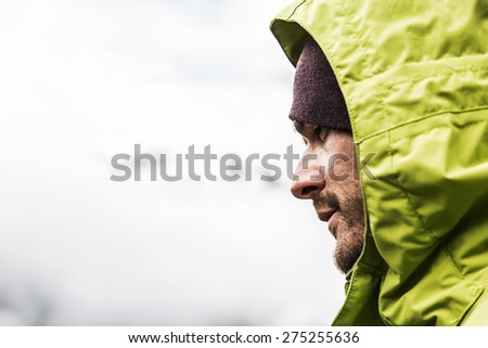 Handsome man profile hooded man on the mountain is looking intently