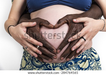 Pregnant mother Caucasian woman ethnic black African-American man father make a heart on her pregnant belly
