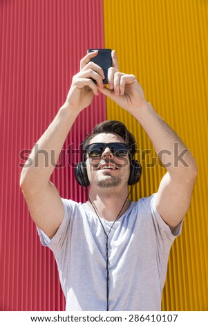 Attractive man with headphones makes selfie photo with his mobile phone
