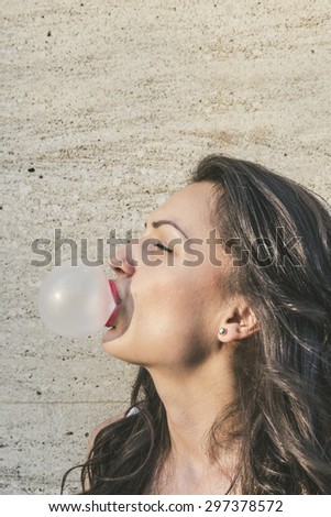 Beauty young woman makes a balloon with a bubble gum,background with copyspace