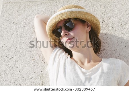 young casual girl wearing a hat and sunglasses relaxed liying on the floor