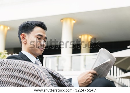 Asian Business man reading a newspaper in Singapore