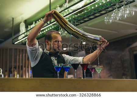 Expert barman is making cocktail at night club