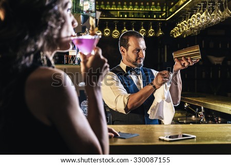 Handsome bartender serving cocktail to beautiful woman in a pub